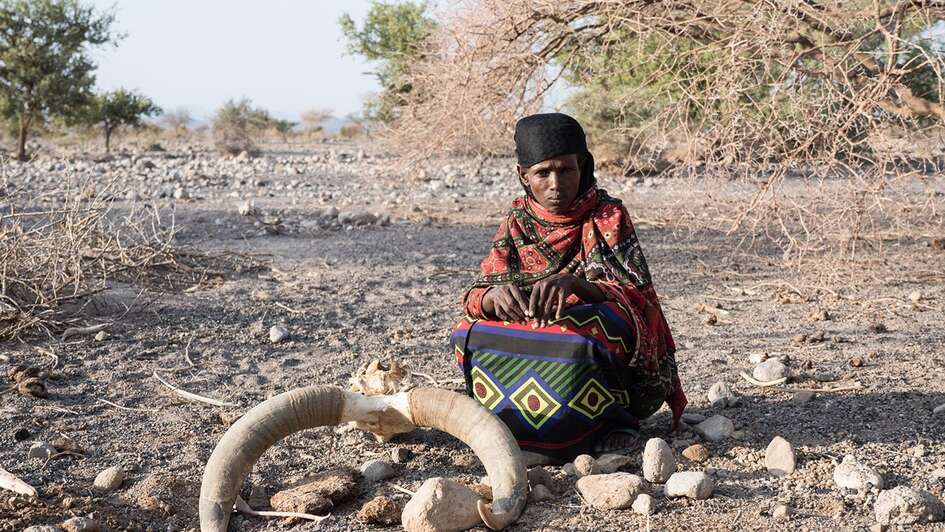 A woman sits in the desert.