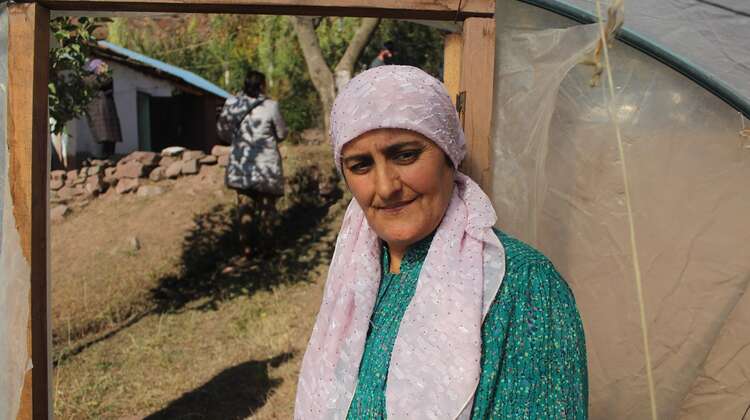 Eine Frau steht am Eingang ihres Gewächshauses