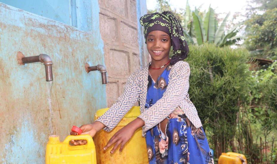 A ten-year-old girl fills a canister with water at a water kiosk