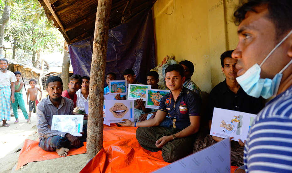 Auf dem Boden sitzende Männer halten Lerntafeln hoch.