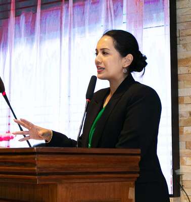 Eine Frau hinter einem Rednerpult spricht in ein Mikrophon.