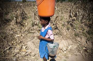 Mädchen trägt Eimer auf dem Kopf