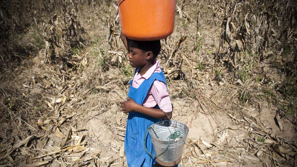 Mädchen trägt Eimer auf dem Kopf