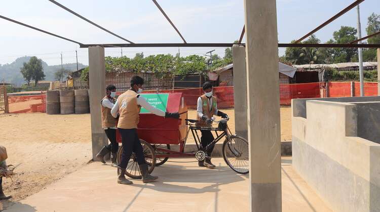 Zwei Männer bringen den Müllwagen zur Sammelstelle, Bangladesch 2021.