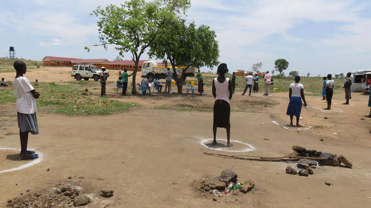 Einige Menschen stehen mit dem Rücken zur Kamera in auf dem Boden aufgezeichnete Kreise.